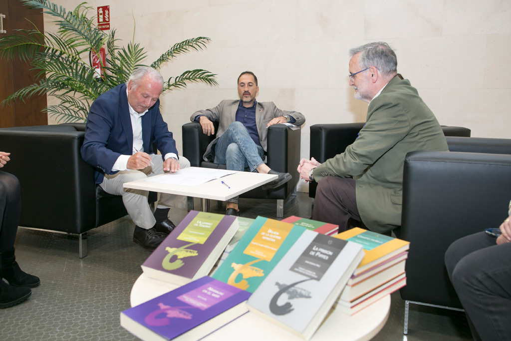 Juan Manuel García Ramos (i) firma la donación ante la presencia del vicerrector Ernesto Pereda y el codirector de la colección, José Gómez Soliño (d).