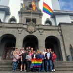 Foto de grupo del rector, los vicerrectores, los directores del Aula y el resto de asistentes al acto de izado de la bandera arco iris en el Edificio Central.